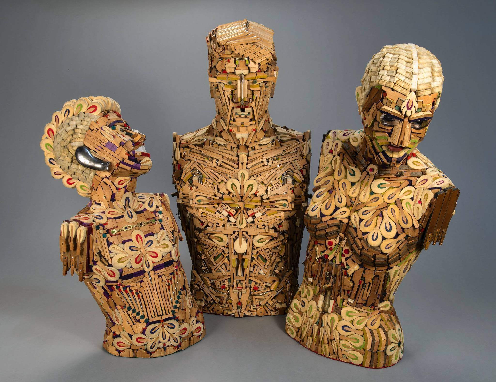 Allen Christian's 2012 work called 'Piano Family' depicting three torsos with
                heads carved out of spare piano parts, standing upright on a gray backdrop.
